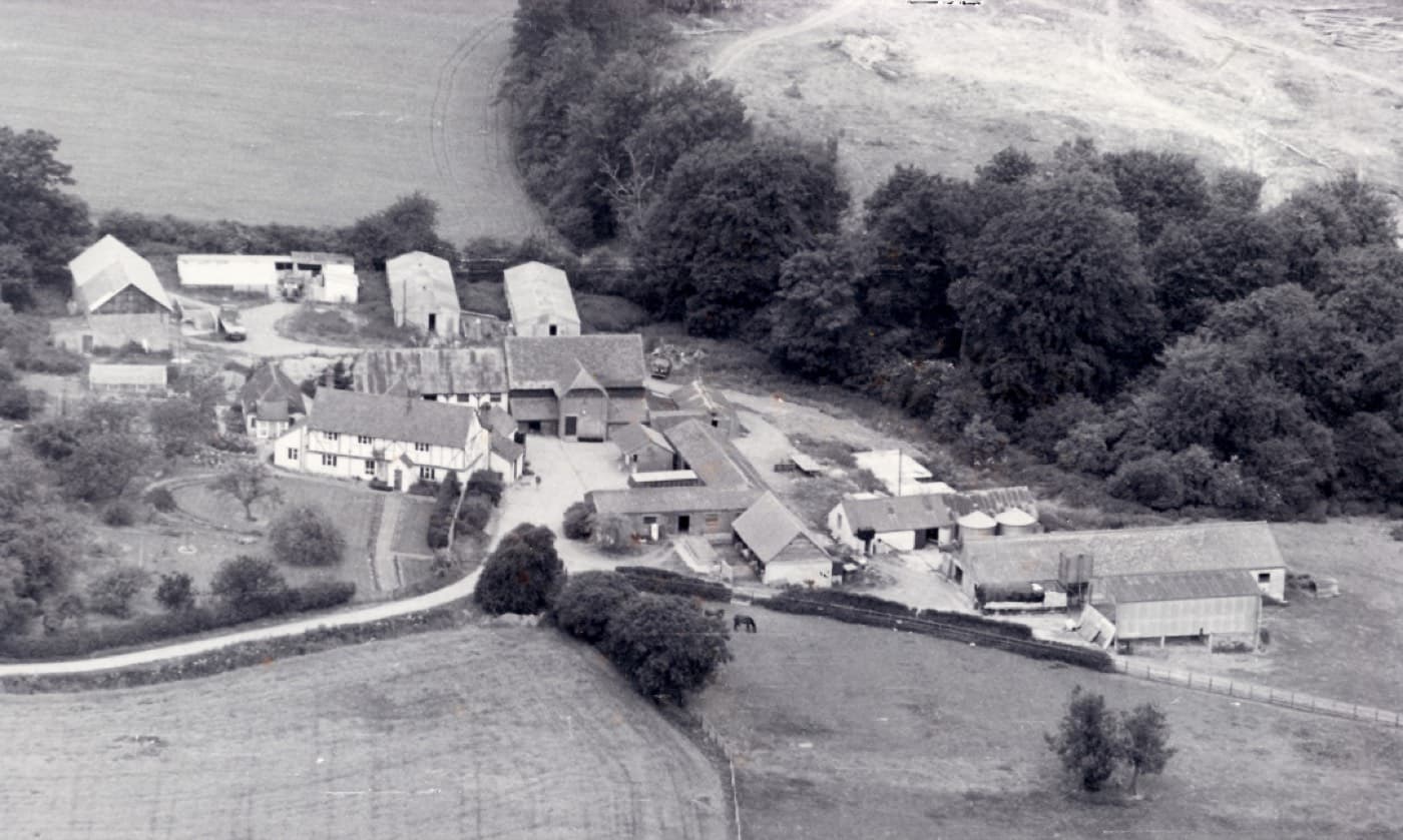 A black and white aerial photograph of Cholsey Grange Farm in 1969, showing the farmhouse, barns and chicken sheds against the woods.