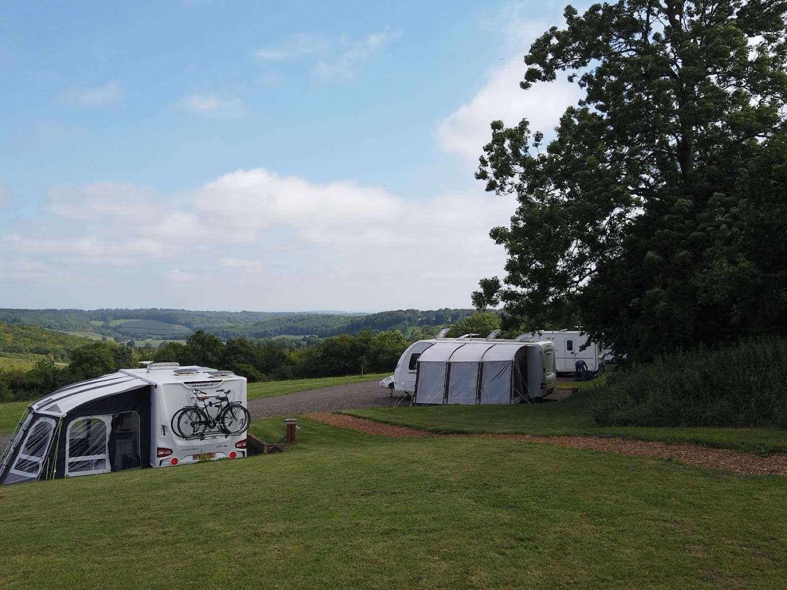 Two caravans pitched at Cholsey Grange with the Hambleden Valley falling away behind them.