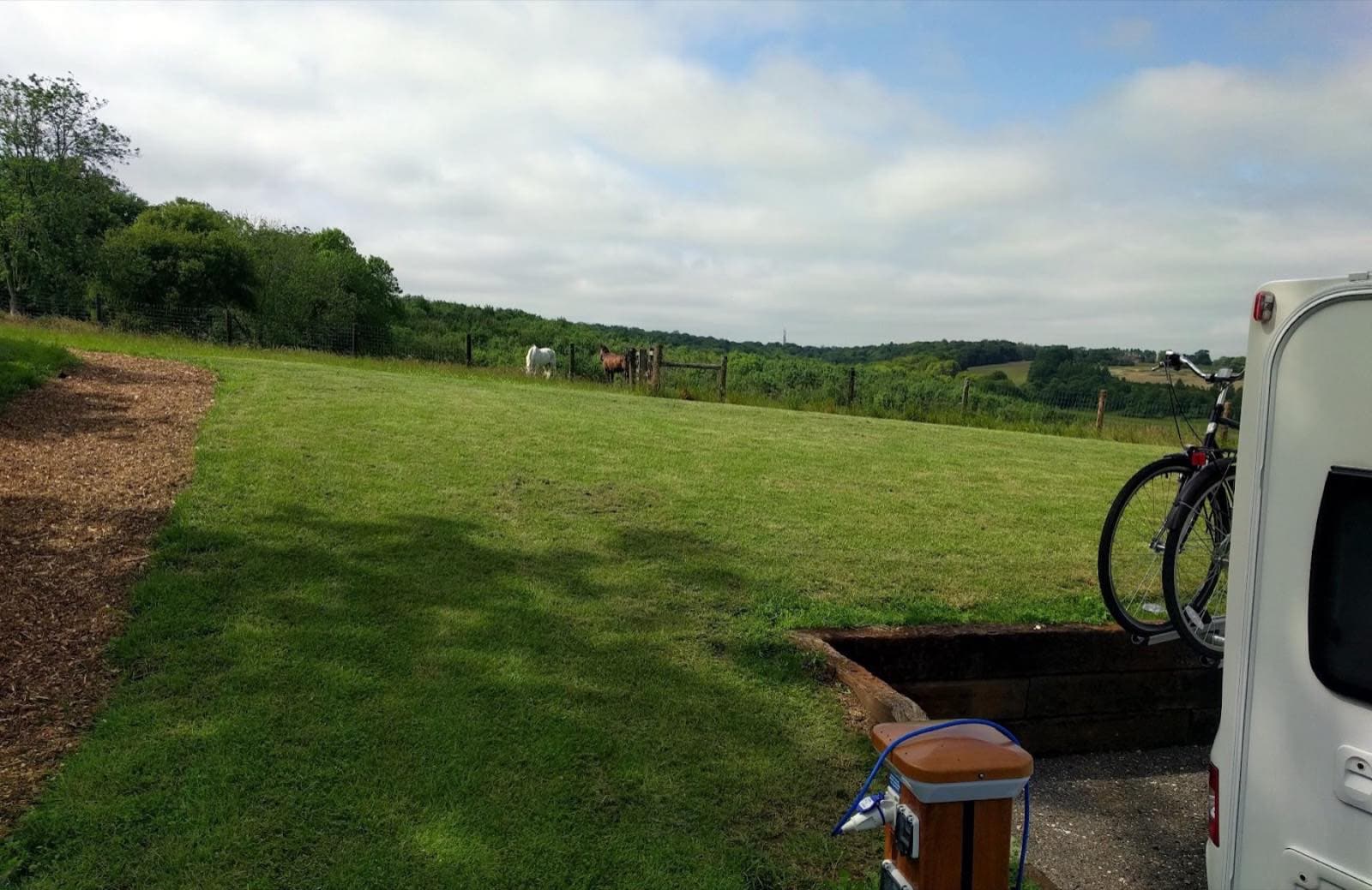 A motorhome pitched next to its service bollard, looking out across the valley.
