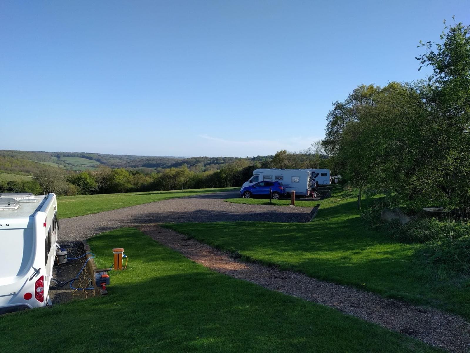 The concrete farm drive leading down to the CL, with caravans pitched at the far end.
