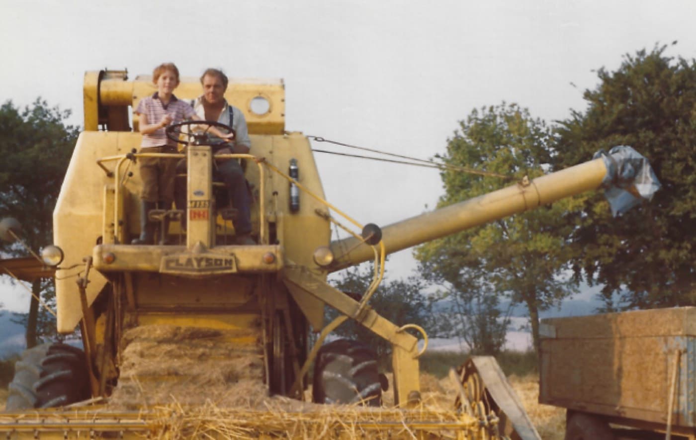 Ted Howard-Jones as a nine-year-old boy sitting beside farm manager Ken Bird at the wheel of a Claeys combine harvester.